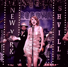 a woman singing into a microphone in front of a sign that says new york broadway