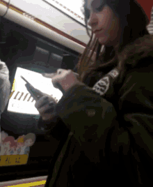 a woman wearing a green jacket and a red hat is looking at her cell phone