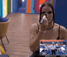 a woman applying makeup in a room with a picture of a man in the background