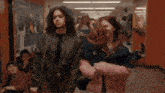 two girls walking down a hallway with one wearing a jacket that says c on it
