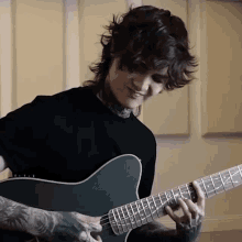 a man in a black shirt plays a guitar