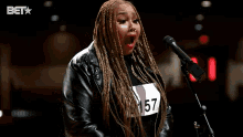 a woman is standing in front of a microphone with the words thank you behind her