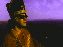 a man wearing a hat with a cross on it and sunglasses