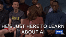 a man in a skull shirt sits in a crowd of people