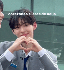 a boy making a heart shape with his hands with the words corazones si eres de nella written above him