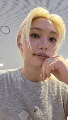 a woman with blonde hair is wearing a gray shirt