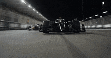 a black race car is driving on a track at night