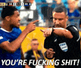 a referee is pointing at a player with the words you 're fucking shit