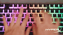 a person typing on a hyperx keyboard with their hands