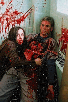a woman is holding a man covered in blood in a bathroom