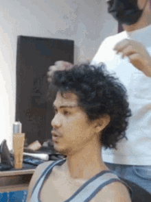 a man with curly hair is getting his hair cut
