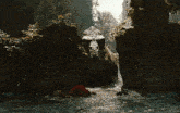 a man in a red shirt is swimming in a river while a dinosaur is behind him