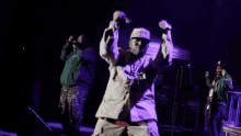 a group of men are performing on a stage with purple lights behind them .