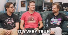 three men are sitting on a couch with one wearing a cardinals shirt
