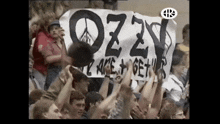 a crowd of people hold up a sign that says ozzy