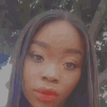 a close up of a woman 's face with red lipstick and long hair .