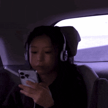 a woman wearing headphones is looking at her cell phone