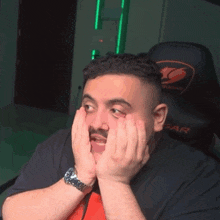 a man wearing a watch is sitting in front of a cougar gaming chair