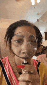 a woman with dreadlocks is looking through a magnifying glass .