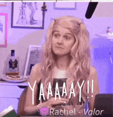 a woman wearing a wig is sitting at a desk with the words yaaaay written on it