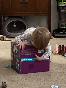 a child is playing with a purple box that says barbie