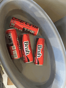 four cans of coke and two cans of brut in a bowl of water