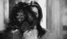 a black and white photo of a woman brushing her hair in front of a mirror .