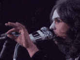 a close up of a person singing into a microphone with a purple background