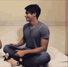 a man is sitting on a bed holding a stuffed animal and smiling .