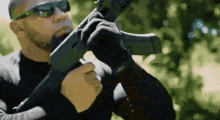 a man wearing sunglasses is holding a gun