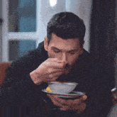 a man with a beard is drinking a cup of coffee