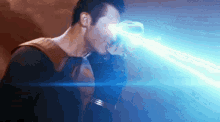 a man in a superhero costume is holding a light beam in his hand .