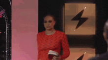 a woman in a red dress stands in front of a lightning bolt on a wall