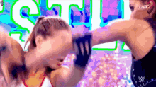 two women are fighting in front of a sign that says ' live ' on it