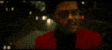 a man wearing a red suit and black shirt is smiling with red paint on his face .
