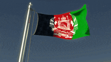 the flag of afghanistan flies in the wind against a blue sky