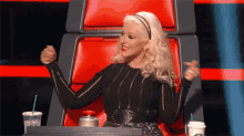 a woman is sitting in a chair with her arms in the air