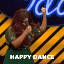 a woman singing into a microphone with the words happy dance written below her