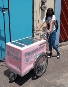 a woman wearing a mask pushes a cart that says gelateria on it