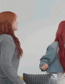 two women with red hair are standing next to each other and one has a pillow in her hand