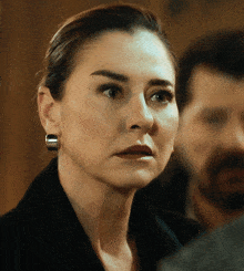 a woman wearing a pair of hoop earrings looks at the camera