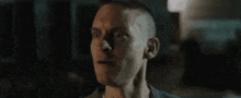 a close up of a man 's face with a shaved head looking at the camera .