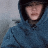 a man wearing a blue hoodie and a hat is sitting in a chair .