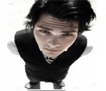 a man wearing a black vest and tie looks up at the camera