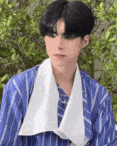 a young man wearing a blue striped shirt and a white scarf around his neck .