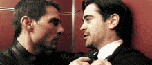 two men are standing next to each other and one is adjusting the tie of the other