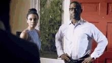a man and a woman standing in front of a red door .