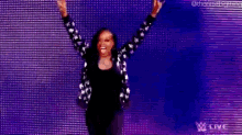 a woman is standing on a stage with her arms in the air and making a rock sign .