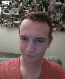 a man in a red shirt is sitting on a couch in front of a wall of pictures .