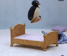 a stuffed penguin is jumping over a small bed